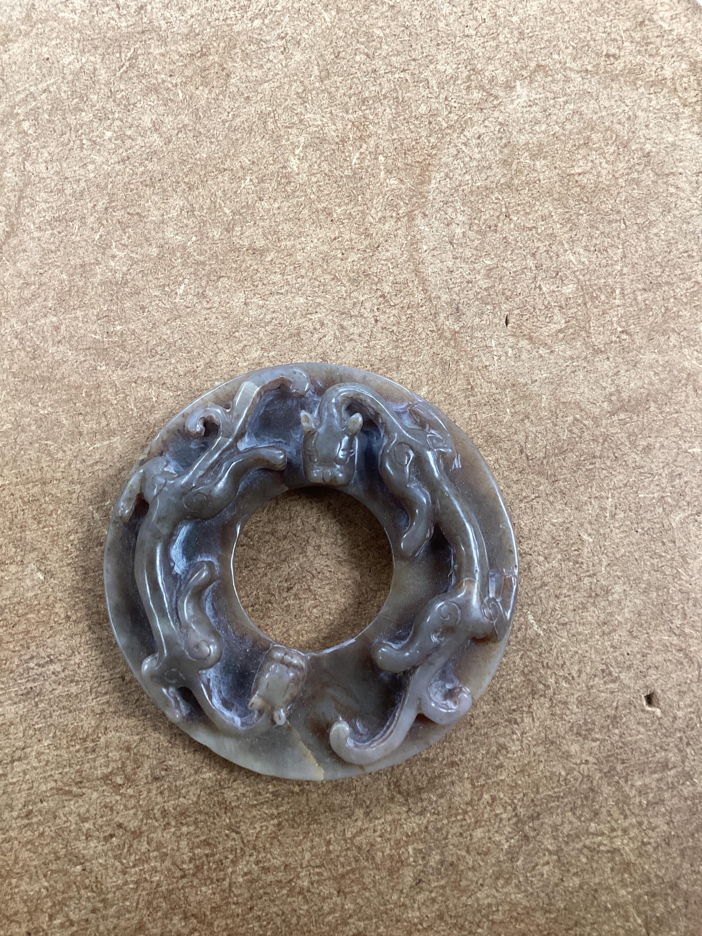 A Chinese brown and celadon jade ‘chilong’ bi disc, probably Ming dynasty, 8cm